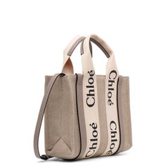 White and grey linen canvas tote bag from Chloé. The Small Woody bag is made of linen canvas detailed with grey calfskin strips, along with the signature Chloé logo ribbon. It is complete with a main compartment designed to fit your mobile phone.Measurements: L26.5 x H20 x W8 cmMade in Italy Chloe Logo, Linen Canvas, Gray Linen, Bags Designer Fashion, Canvas Tote Bag, Canvas Bag, Canvas Tote, Calf Skin, Chloe