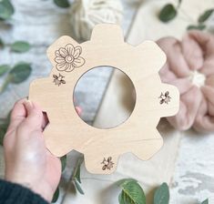 a person holding a wooden frame with flowers on it