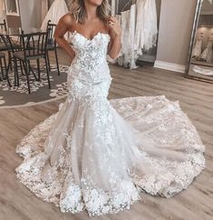 a woman standing in front of a mirror wearing a wedding dress with flowers on it