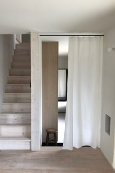 an open door leading to a room with white curtains and wooden steps in front of it