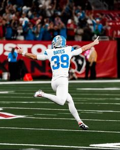 a football player is running on the field with his arms in the air and one hand out