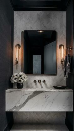 a bathroom with marble counter tops and gold fixtures, along with a black wall mounted mirror