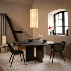 a dining room table with two chairs and a vase on the table next to it