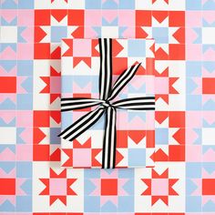 a present wrapped in black and white ribbon on a pink and blue checkered background