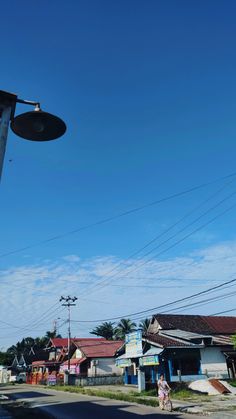 a street light sitting on the side of a road next to a blue sky with clouds