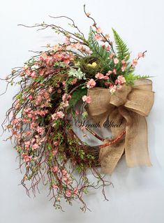 a wreath with pink flowers and greenery tied to it