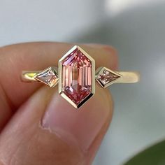 Pink 2 Ct Hexagon Cut Moissanite Engagement Ring, Hexagon Cut Ring, Moissanite Engagement Ring, Three Stone Ring ✥ 𝐌𝐚𝐢𝐧 𝐒𝐭𝐨𝐧𝐞 𝐃𝐞𝐭𝐚𝐢𝐥𝐬 ↣ Shape: Hexagon Cut ↣ Type: Moissanite ↣ Weight: 2 Ct (App.) ↣ Color: Pink ↣ Clarity: VVS ↣ Making Process: Handmade - Crafted by our experienced team ↣ Excellent Cut and Polish by Diamond Artician ✦ Side Stone Details ↣ Shape: kite ↣ Color: Pink ↣ Clarity: VVS ✥ 𝐑𝐢𝐧𝐠 𝐃𝐞𝐭𝐚𝐢𝐥𝐬 ↣ Band Width: 1.8 mm (± 0.10) [Customization Possible] ↣ Meta Pink Moissanite Engagement Ring, Pink Moissanite Ring, Bezel Set Engagement Ring, Hexagon Diamond, Bezel Set Ring, Pink Sapphire Ring, Bezel Ring, Diamond Anniversary Rings, Moissanite Ring