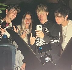 four people taking a selfie in the back of a car with their cell phones