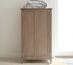 an armoire with towels on top of it in front of a window and rug