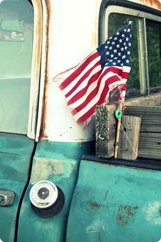 an old truck with the american flag sticking out of it's side door window