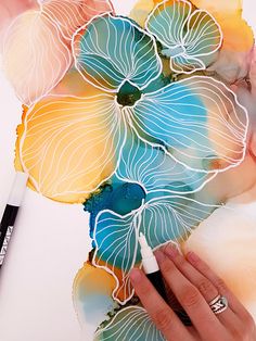 a person is drawing flowers with colored pencils and watercolor paints on white paper