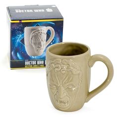 a ceramic mug with a face on it next to a boxed box for doctor who