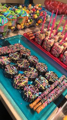 there are many different types of candy on the table and in front of it is an assortment of cupcakes