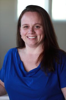 a woman in a blue shirt smiling at the camera