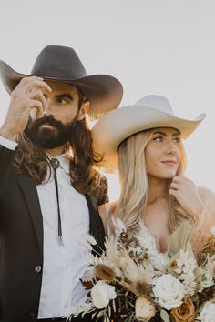 a man in a cowboy hat standing next to a woman wearing a white dress and black suit