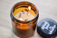 a candle that is sitting next to a canister on a wooden table with some candles in it