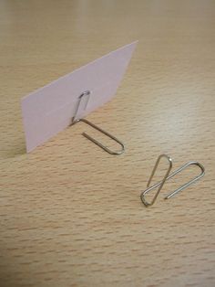 a pair of paper clips sitting on top of a wooden table