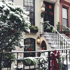 a house covered in snow with christmas decorations on the front door and steps leading up to it