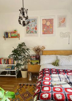 a bedroom with a bed, plant and pictures on the wall