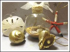 three ornaments are sitting on a table together, including shells and seashells in glass ornament