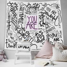 a room with a bed, chair and large wall mural that says you are written all over it