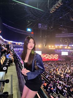 a woman standing in front of an audience at a sporting event holding a pink toothbrush