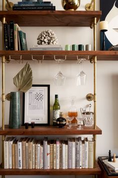 a shelf filled with books and glasses next to a wine glass on top of a table