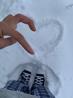 a person standing in the snow making a heart shape with their hand and foot prints