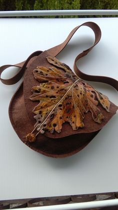 a brown hat with leaves on it sitting on top of a white table next to a window