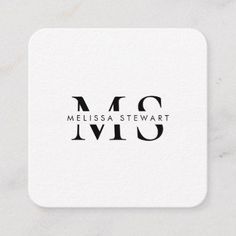 a white square coaster with the word mcs in black ink on top of it