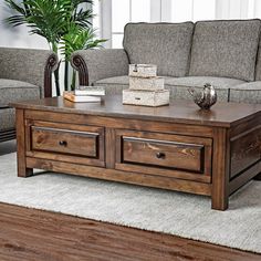 a wooden coffee table sitting on top of a rug in front of a gray couch