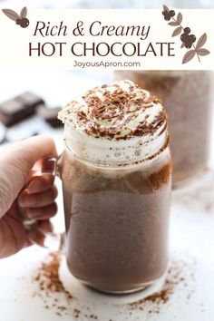 hot chocolate in a glass mug with whipped cream and cinnamon sprinkles on top