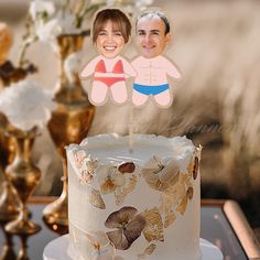 two people standing behind a cake with flowers on it