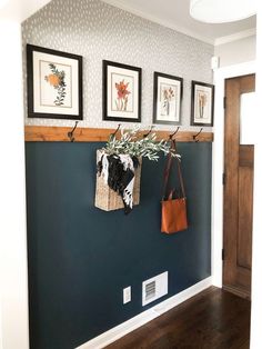 a wall with three pictures hanging on it and two purses hanging from the hooks