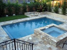 a backyard with a swimming pool surrounded by stone steps and fenced in grass area