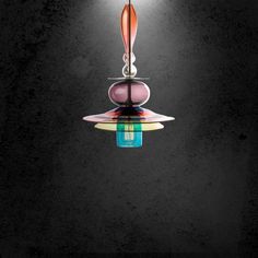 a multi - colored light hanging from a ceiling fixture in a dark room with black walls