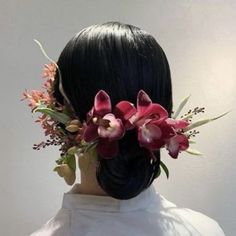 the back of a woman's head with flowers in her hair, wearing a white shirt