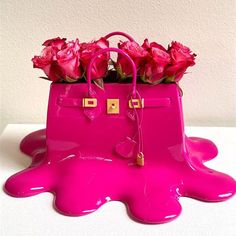 a pink purse with flowers in it sitting on top of a white table next to a wall