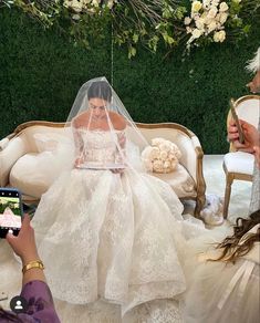 the bride is taking a photo with her cell phone while she sits on a couch