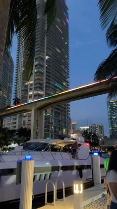 a white boat traveling down a river next to tall buildings in the city at night