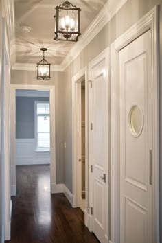 an empty hallway with two white doors and a chandelier