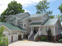 a large white house with green roofing and stairs leading up to the front door