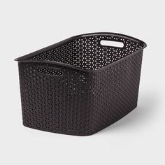 a black plastic basket with holes on the sides and handles, sitting in front of a white background