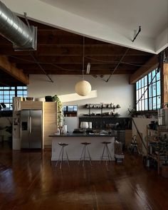 an open kitchen and living room with wood floors, exposed ceilings, and large windows