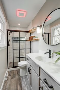 Master bathroom remodel includes glass shower doors with matte-black grids, enclosing an all-tile shower that features a bench seat and Caribbean-blue tiled niche, swarm gray vanity with white marble top, distressed vinyl plank floor, and floating live-edge wood shelving