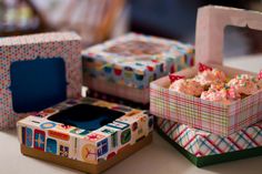 three boxes with different designs on them sitting on a table next to each other and one has a piece of cake in it