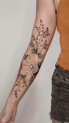 a woman's arm with flowers and leaves tattooed on the left side of her arm