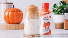 an orange pumpkin sits next to a jar of whipped cream