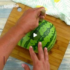 a person cutting up a watermelon on top of a wooden cutting board