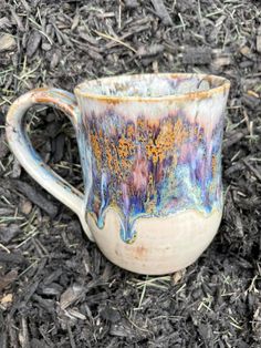 a coffee cup sitting on the ground with grass and mulch around it's edges